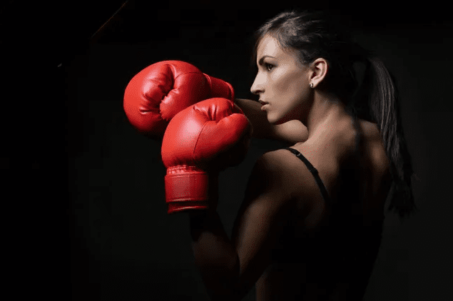 A woman wearing red boxing gloves and posing for the camera.